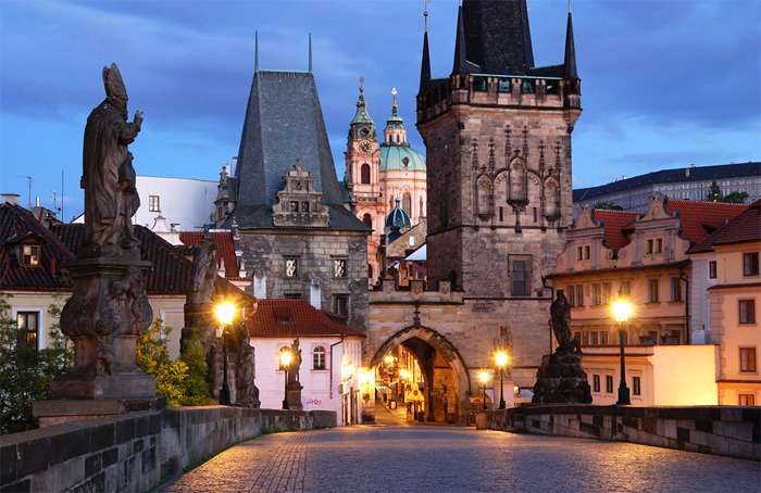 Na fotce konec Karlova mostu v Praze. Je podvečer. Fotka ukazuje jak romantická je Praha.